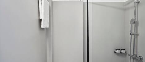 A modern shower with a handheld showerhead and a wall-mounted faucet.