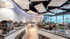 Een moderne buffetopstelling met diverse food stations, roestvrijstalen serviesgoed en een fietswiel als decoratief element.