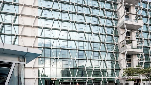 Een modern gebouw met een geometrisch gevelontwerp en een zwembad ervoor.