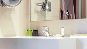 Un baño moderno con un lavamanos blanco, un espejo, toallero y un inodoro.