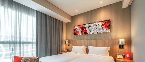 Una habitación de hotel con una cama grande, dos mesitas de noche, un sofá y un adorno en la pared.
