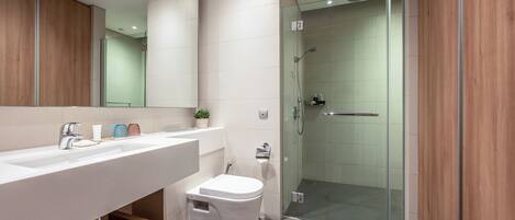 A modern bathroom with a large mirror, white sink, and glass shower enclosure.