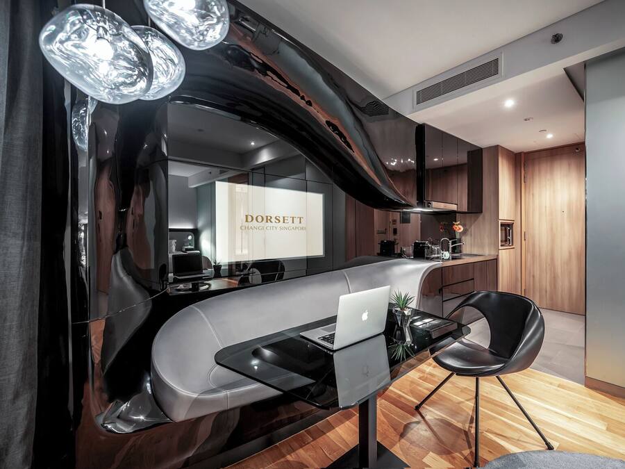 Una cocina moderna con una encimera curva, una computadora portátil y una silla.