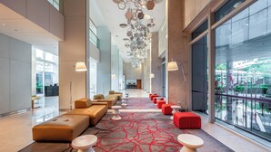 Een moderne hotellobby met een lange receptiebalie, comfortabele zithoeken en grote ramen met uitzicht op het omliggende landschap.