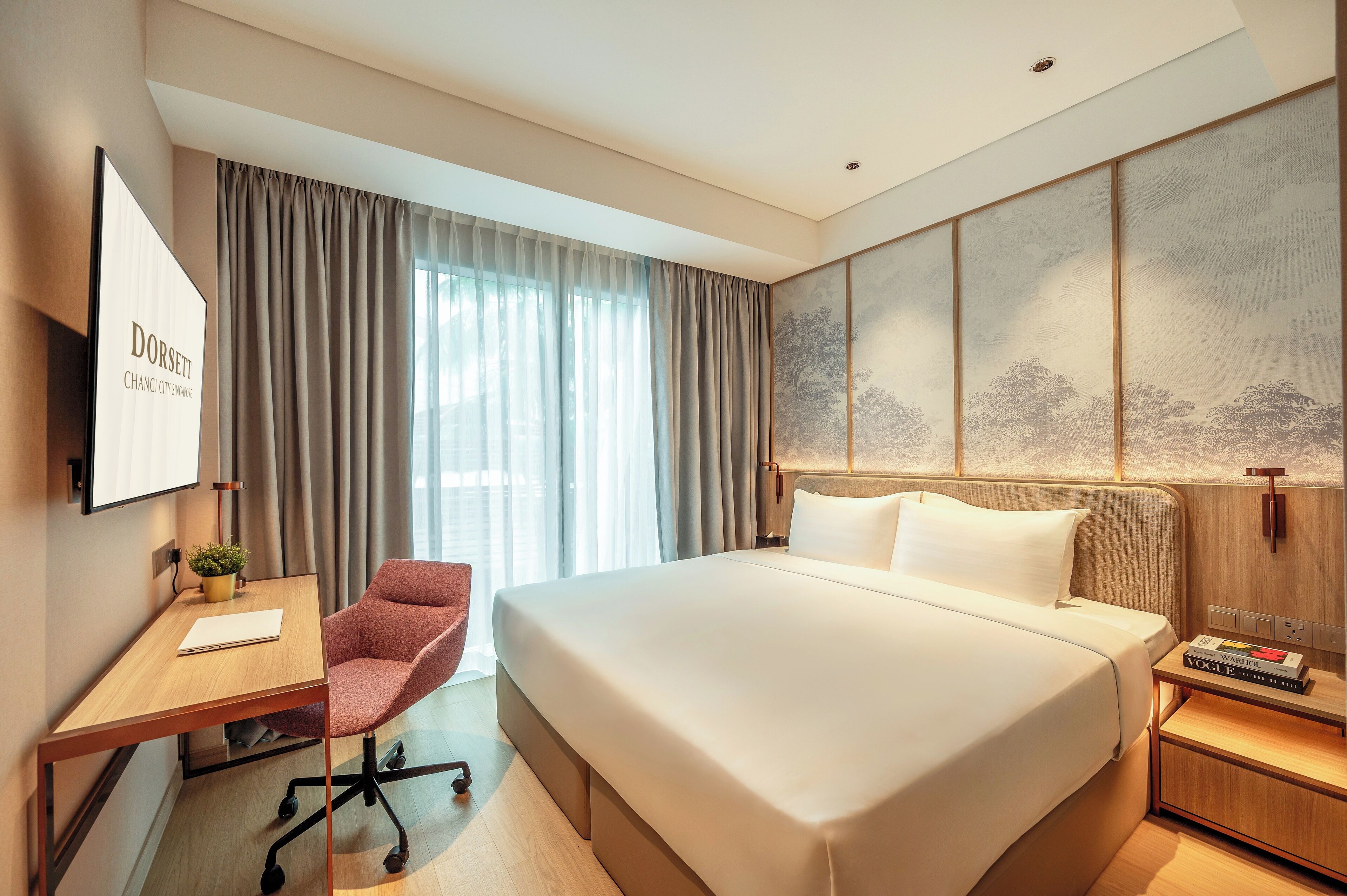 A hotel room with a large bed, a desk with a chair, a TV, and a wall with a nature-themed artwork.