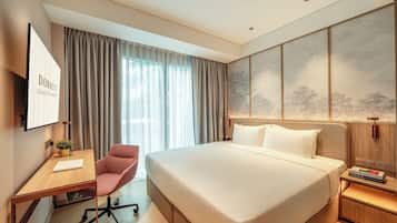 Hotelkamer met een groot bed, een bureau met stoel, een televisie en een wand met natuurkunst.