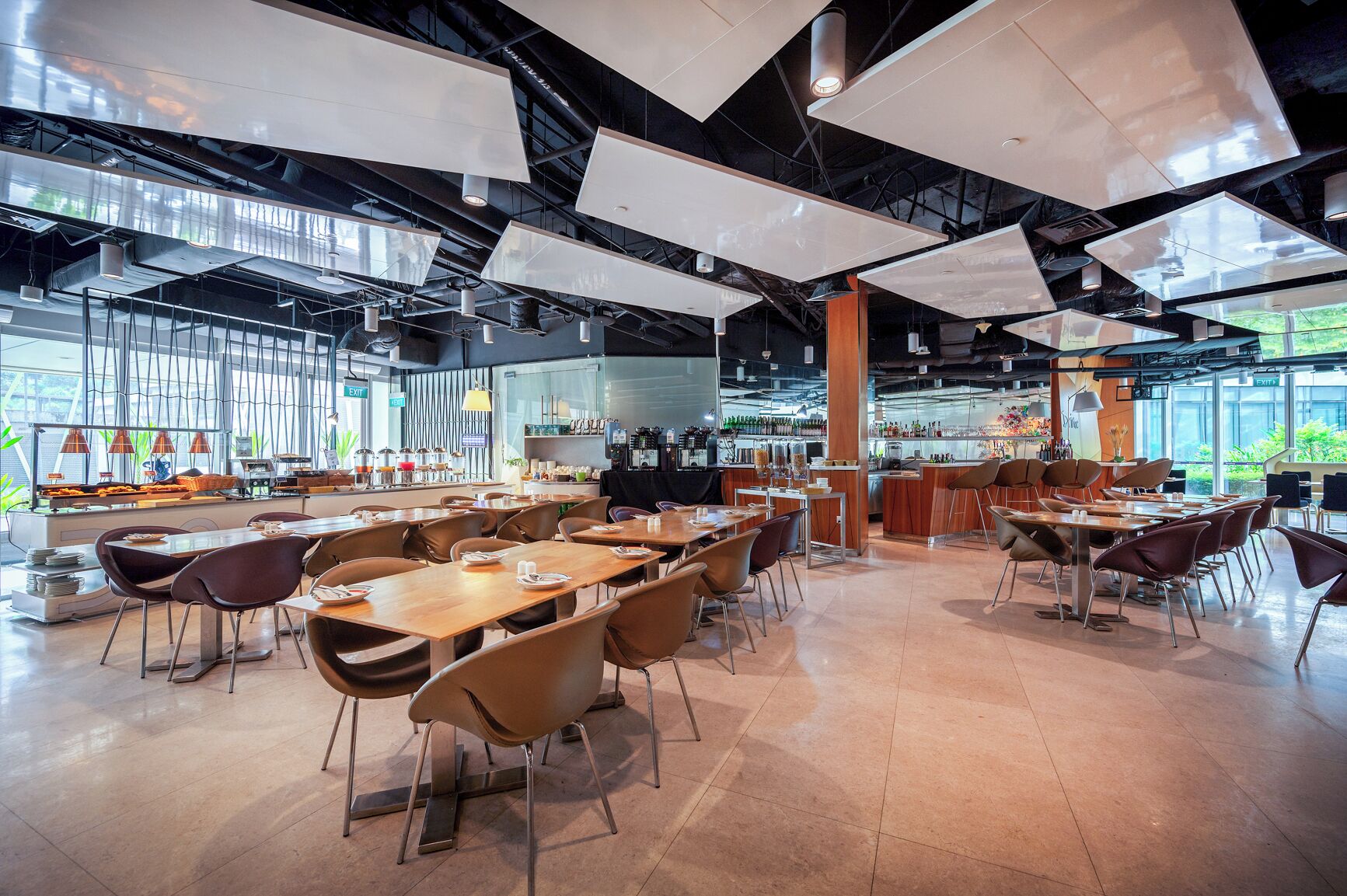 Un restaurante espacioso con techos altos, iluminación colgante moderna y una zona de bar.