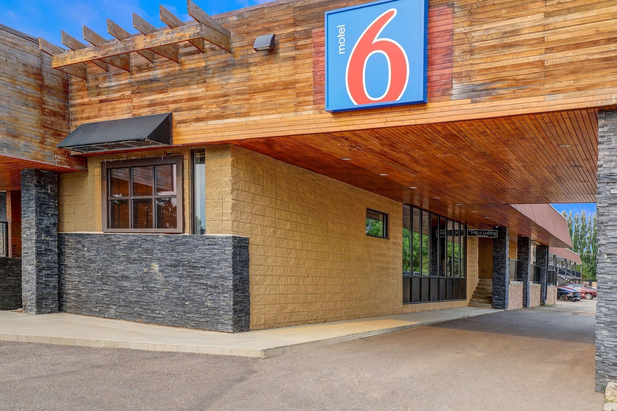 A motel with a prominent '6' sign, stone facade, and a covered outdoor area.
