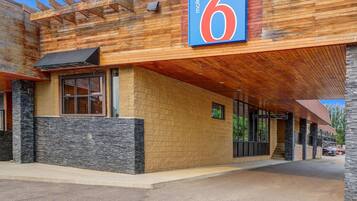 A motel with a prominent '6' sign, stone facade, and a covered outdoor area.
