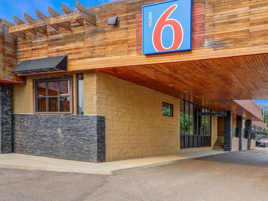 A motel with a prominent '6' sign, stone facade, and a covered outdoor area.