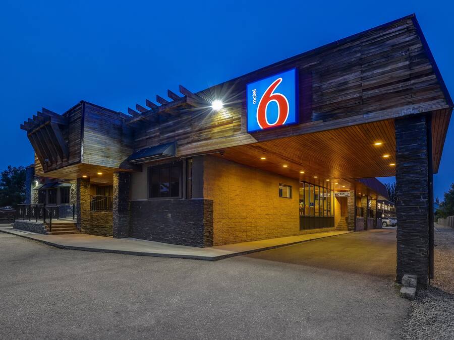 A motel with a '6' sign, a covered entrance, and a gravel driveway.