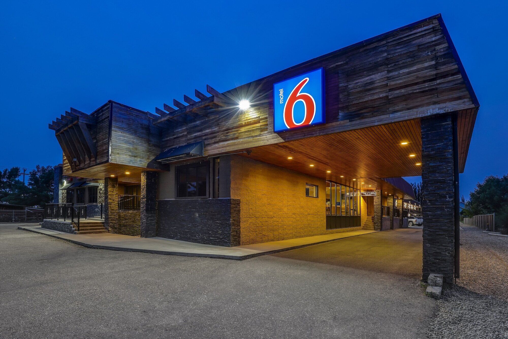 Ein Motel mit einer auffälligen '6' Beschilderung, einem überdachten Eingang und einer Stein-Fassade.