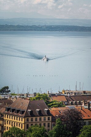 Paisaje urbano frente al agua con un barco en el agua, edificios de arquitectura diversa y un cielo despejado.