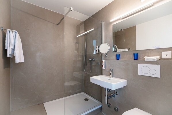 A modern bathroom with a glass-enclosed shower, a white sink, and a mirror above it.
