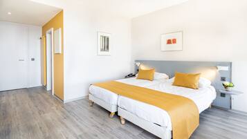Una habitación de hotel moderna con una cama grande, una mesita de noche y otra mesita auxiliar.