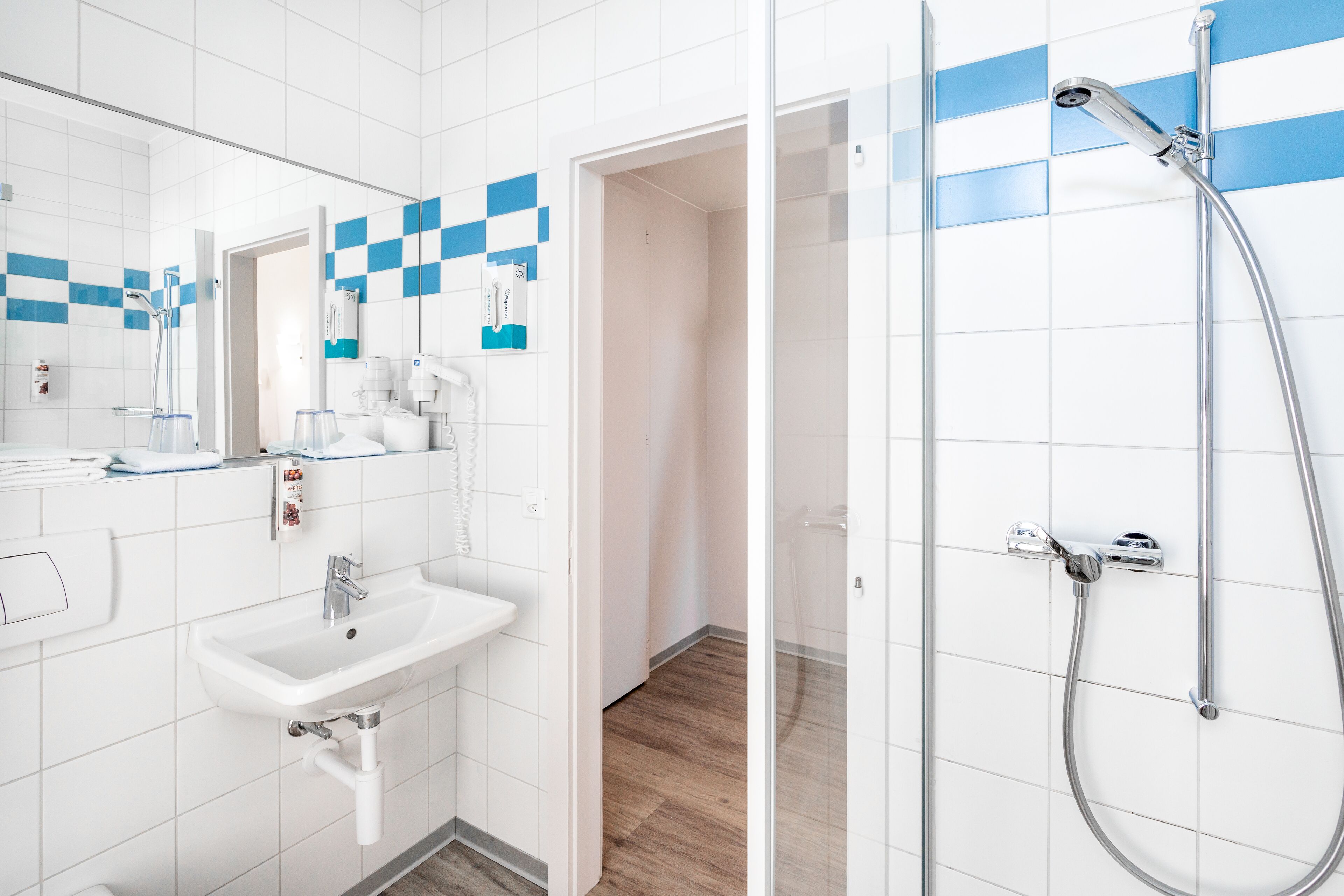 A modern bathroom with a white sink, mirror, and shower.