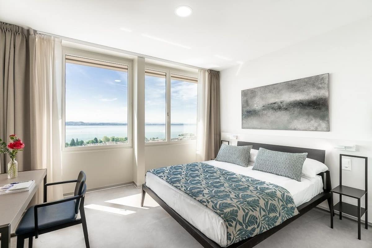 Una habitación de hotel moderna con una cama grande, un escritorio y vistas al mar.