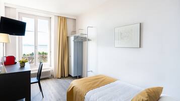 Una camera d'albergo con un letto, una scrivania con una sedia, una televisione e una finestra con tende.