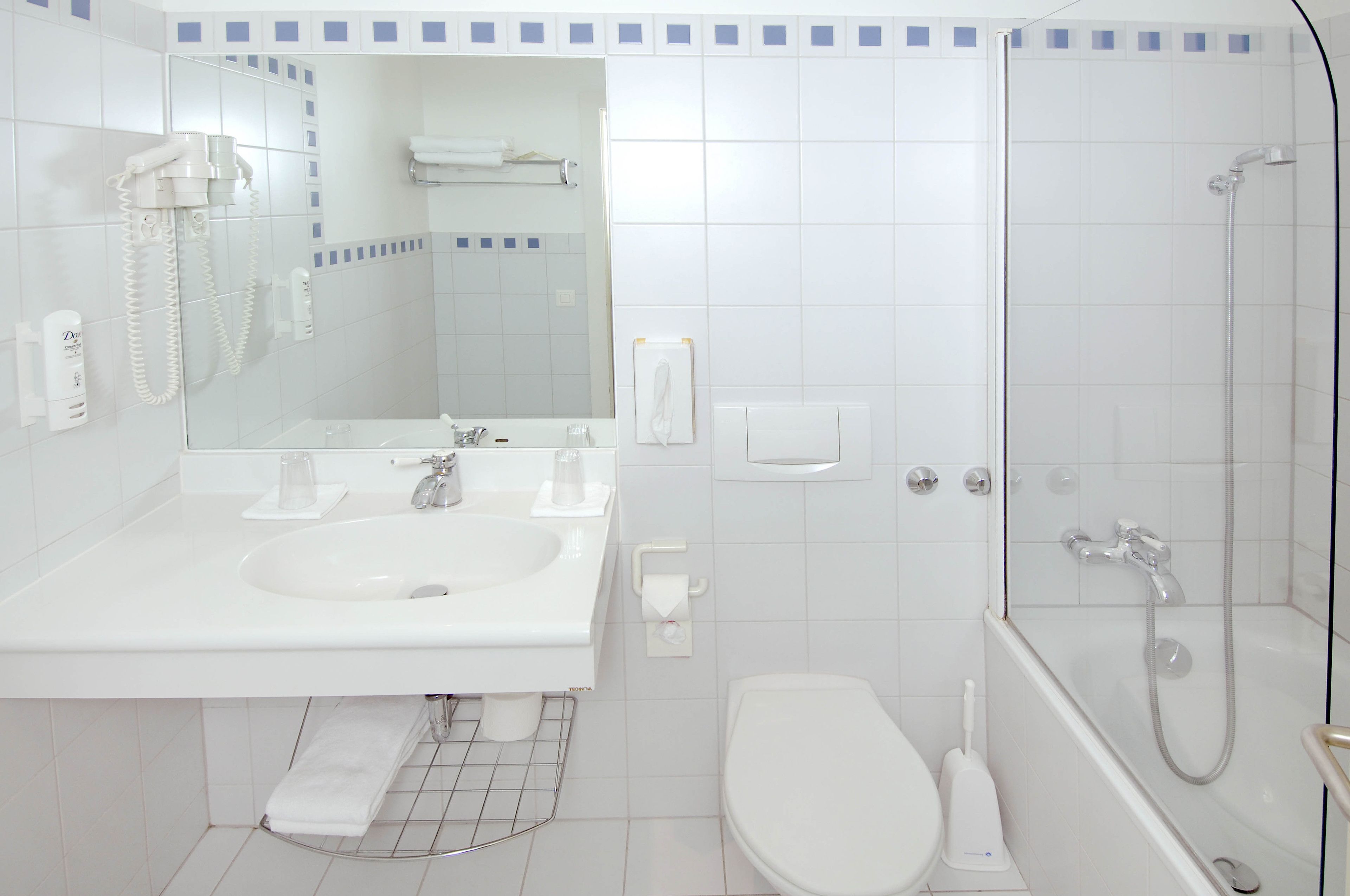 Casa de banho moderna com lavatório branco, espelho, sanita e chuveiro.