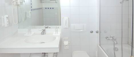 A modern bathroom with a white sink, mirror, toilet, and shower.