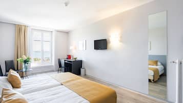 Ein Hotelzimmer mit Bett, Schreibtisch, Stuhl, Fernseher und einem großen Spiegel.