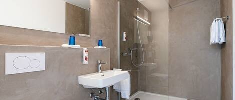 Un baño moderno con cabina de ducha de vidrio, un lavabo blanco y un espejo.