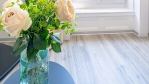 A room with a view of the sea through a window with white shutters, a vase with flowers on a table, and a light-colored floor. - Hôtel Alpes & Lac (Neuchatel)