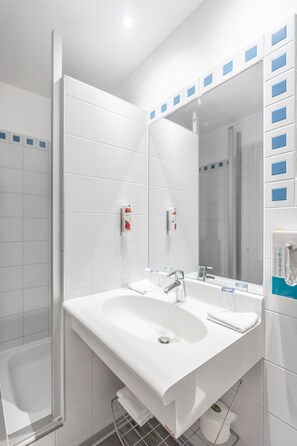 Un baño moderno con lavamanos blanco, espejo y ducha.