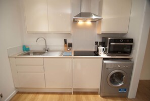 A compact kitchen with a sink, stove, microwave, and washing machine.