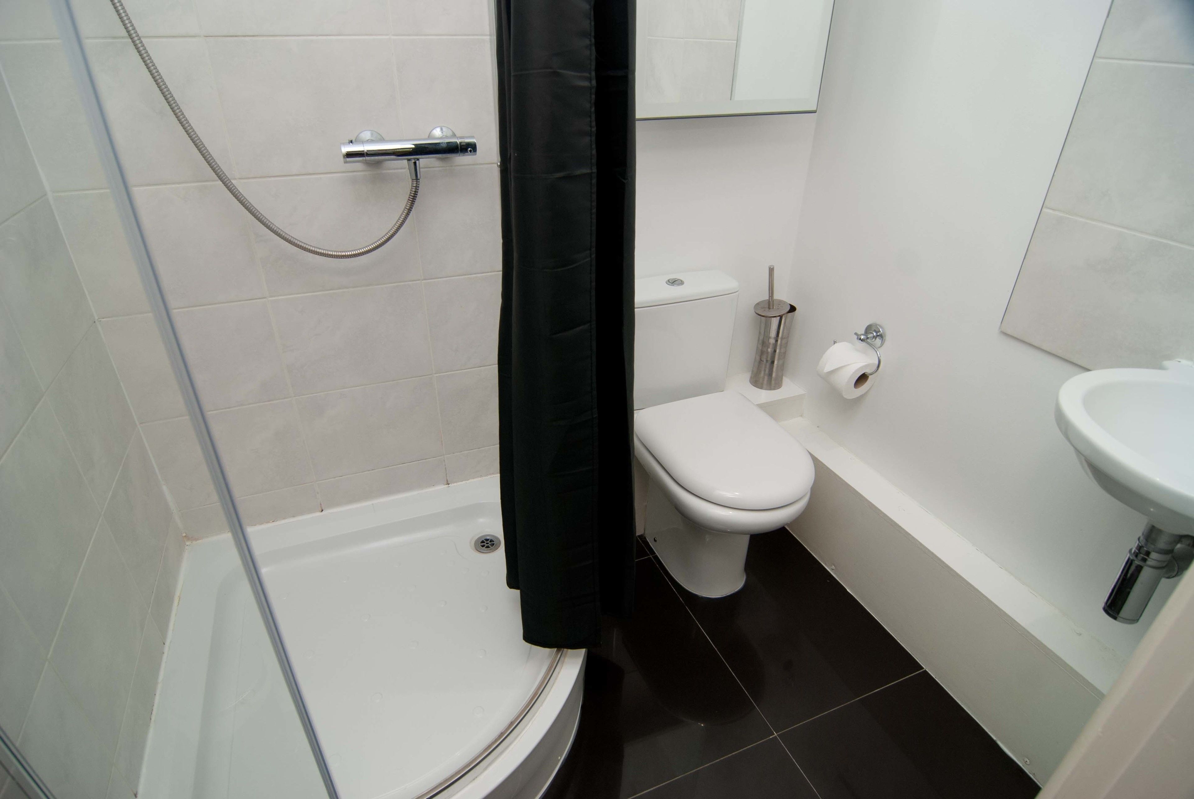 A bathroom with a glass-enclosed shower, a toilet, and a sink.