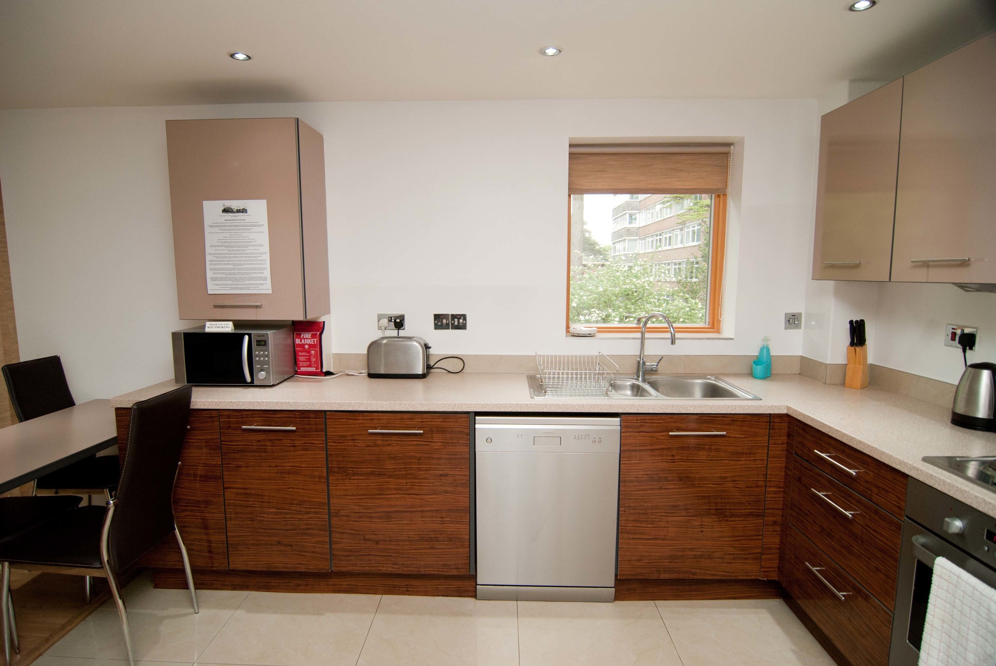 A modern kitchen with wooden cabinets, a dishwasher, a toaster, and a sink.