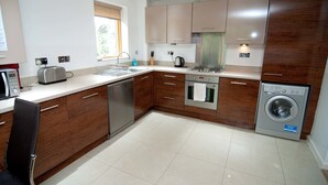 Una cocina moderna con armarios de madera, electrodomésticos de acero inoxidable y lavadora integrada.