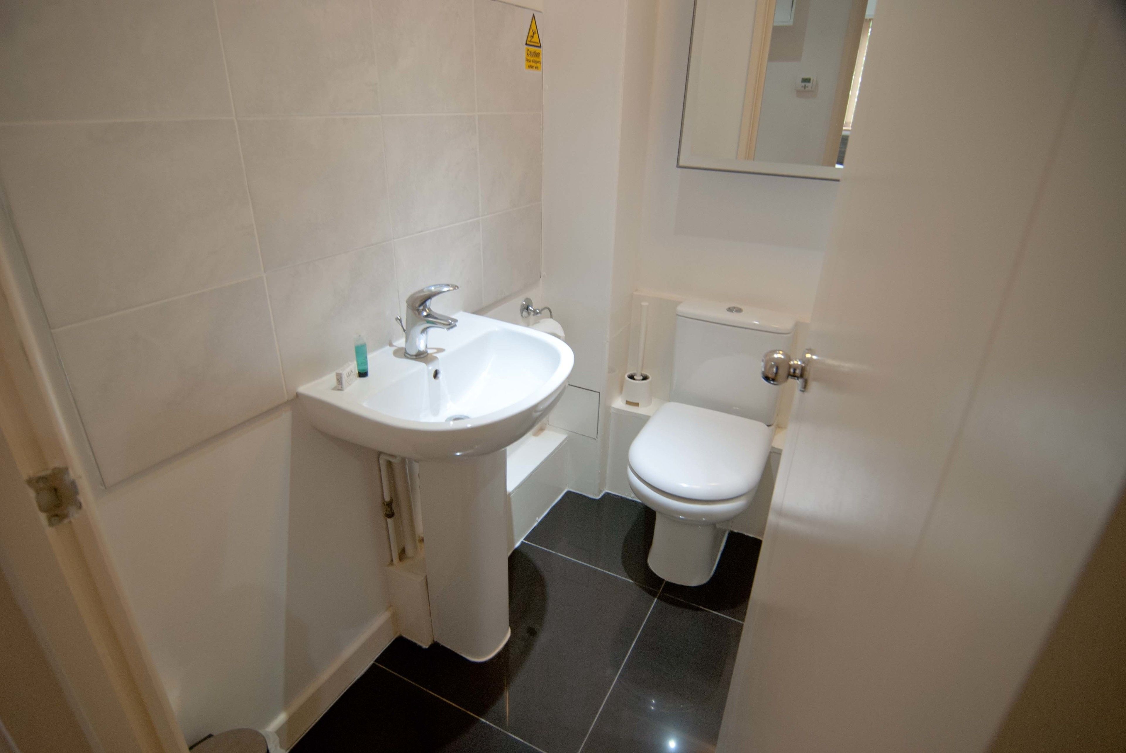 A small, clean bathroom with a white sink, toilet, and bathtub.
