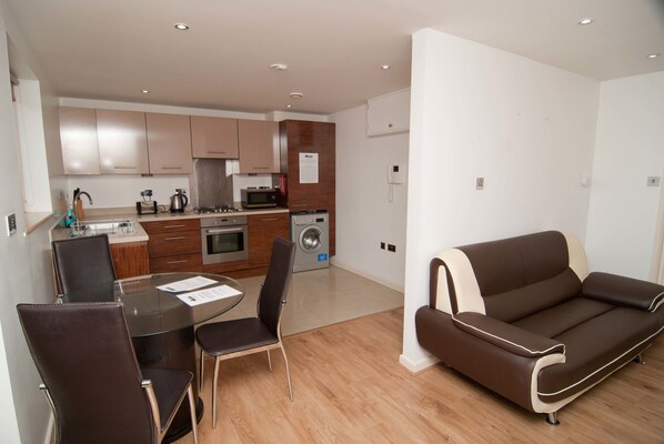 A modern apartment with a dining area, kitchenette, and a living room with a sofa. - Southampton Serviced Apartment (Southampton)