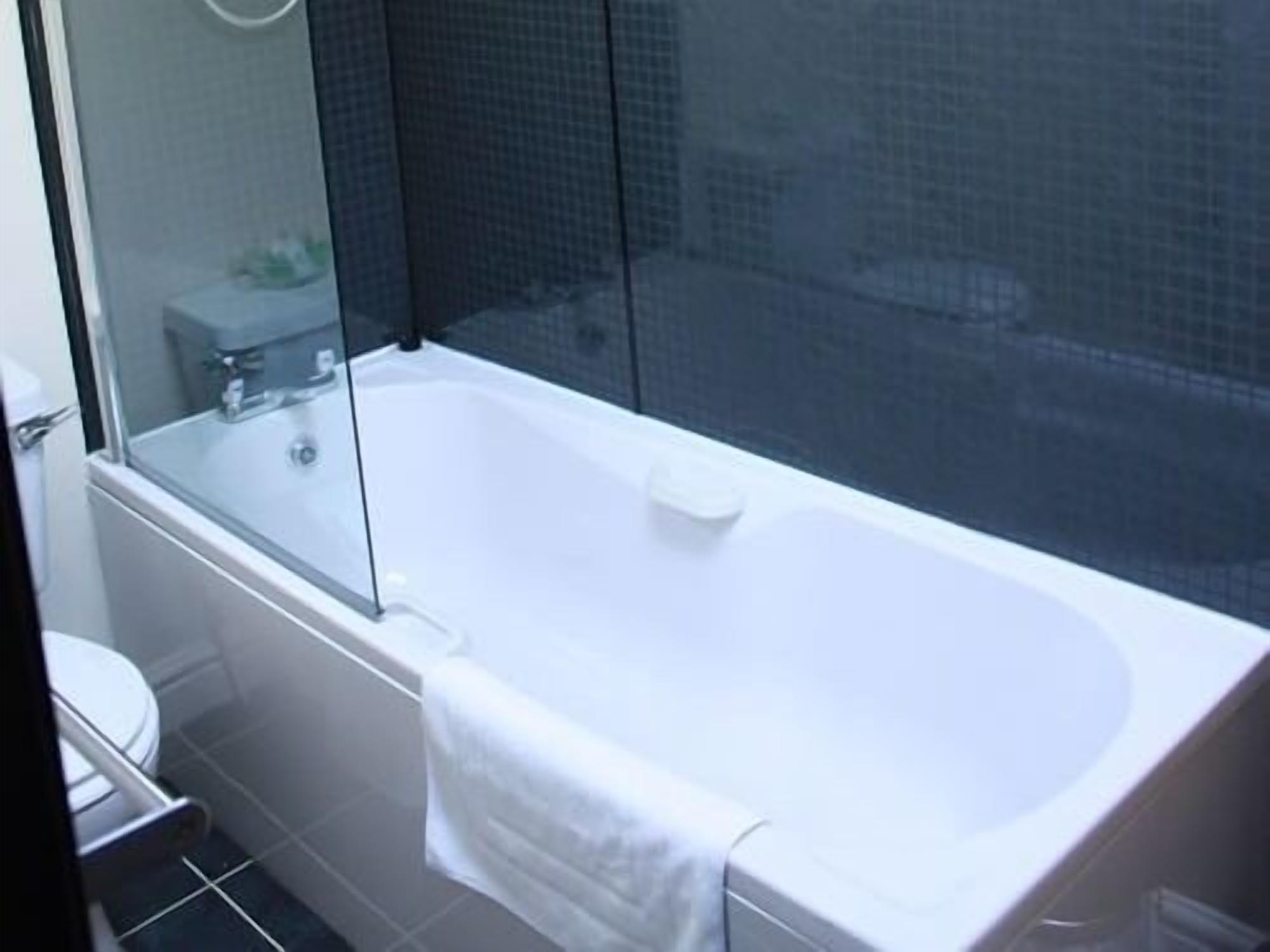Une salle de bain moderne avec une douche à parois de verre, une baignoire blanche et des toilettes apparentes.