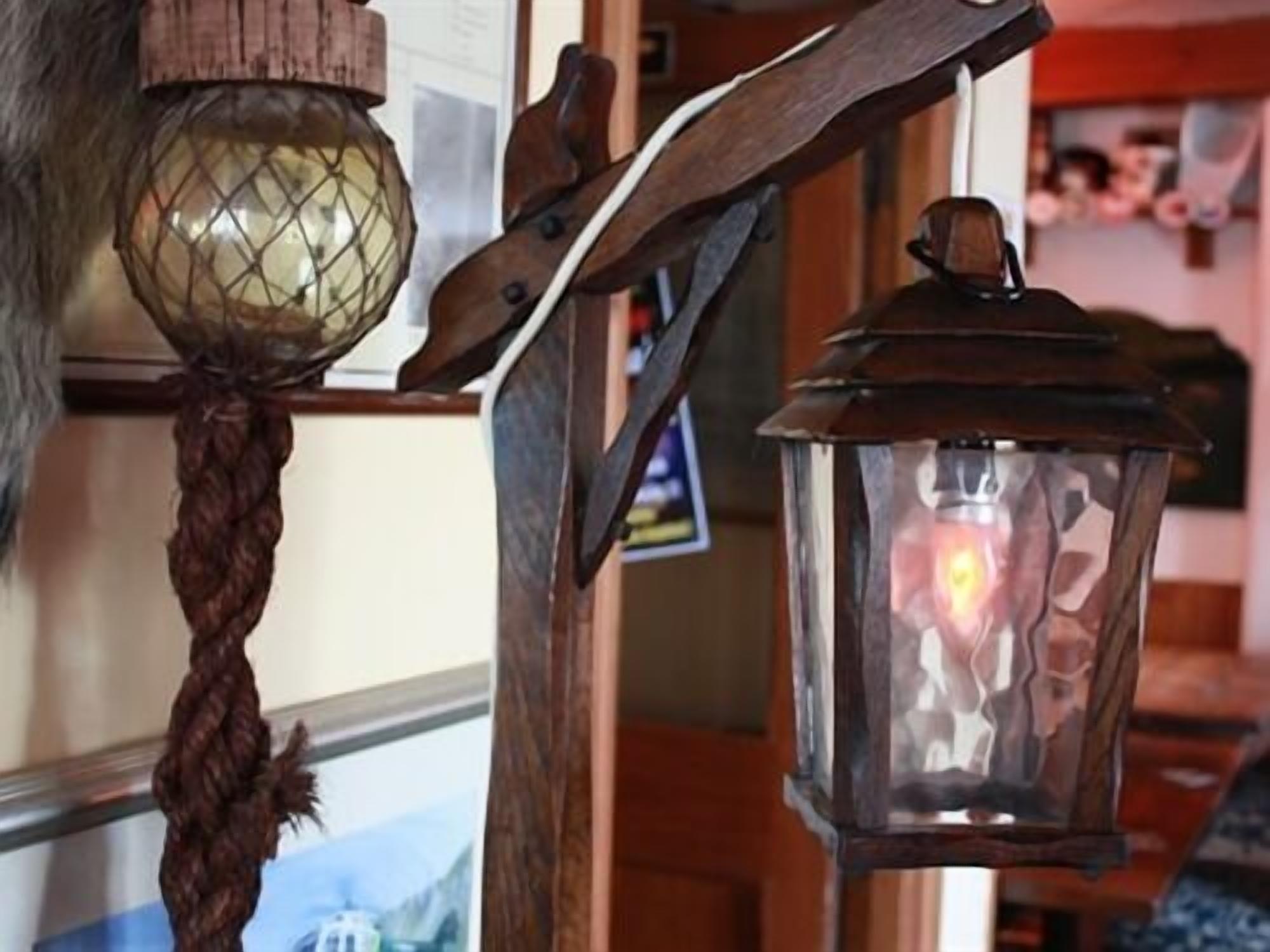 A rustic interior with a wooden spiral staircase, a wooden door, and a wall-mounted lantern.