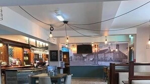 A restaurant with a bar area, wooden flooring, and a mural on the back wall. - The Farmers Arms (Richmond)