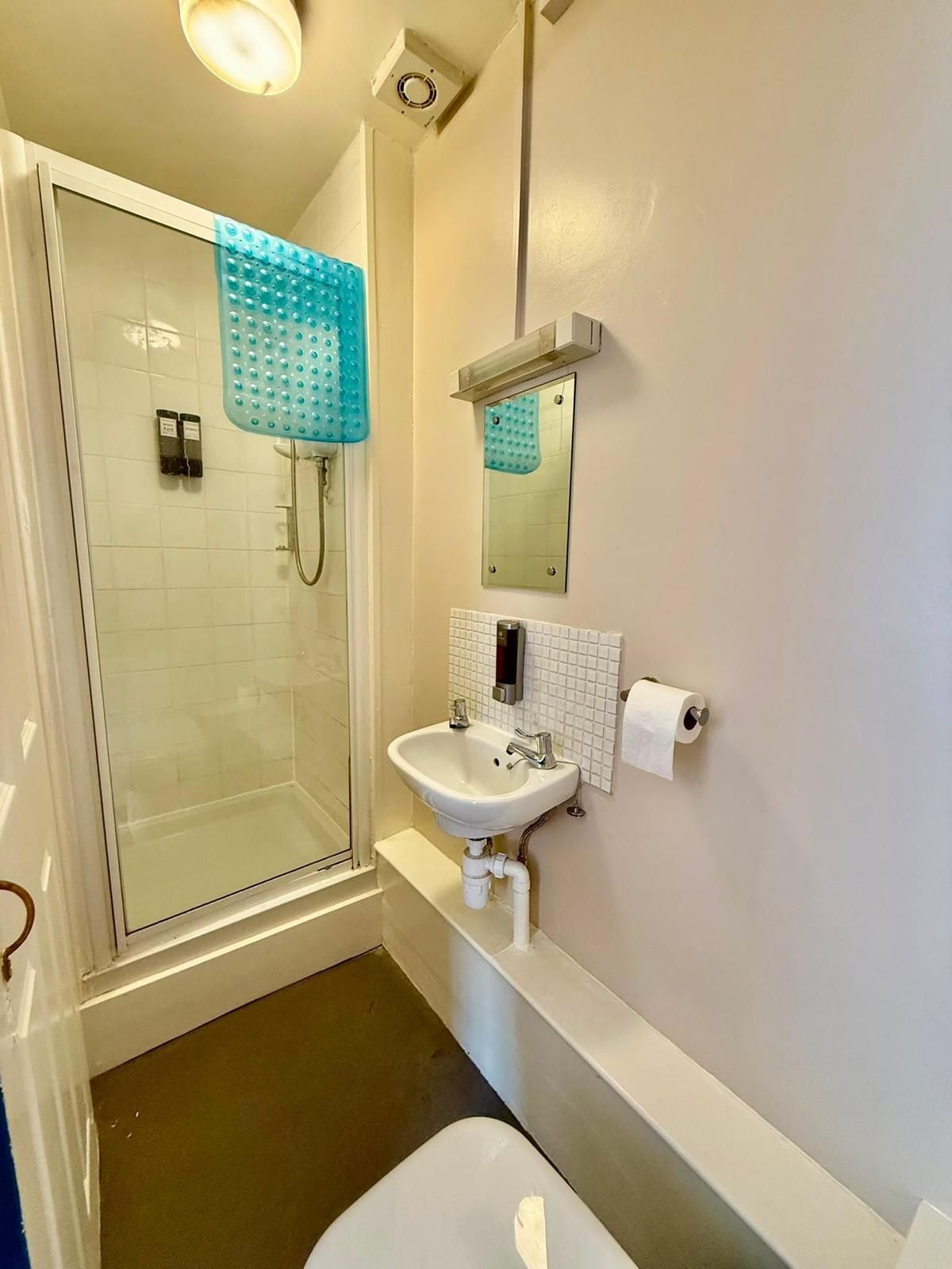 Un baño con cabina de ducha de vidrio, un lavabo blanco, un espejo y un inodoro.