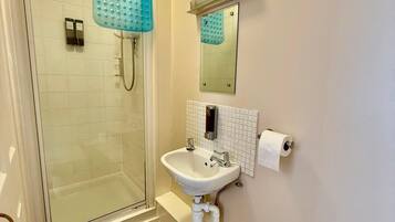 Un baño con cabina de ducha de vidrio, un lavabo blanco, un espejo y un inodoro.