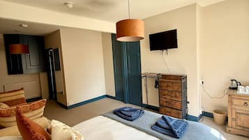 Una habitación de hotel con una cama, un televisor de pantalla plana, un aparador de madera y una lámpara.