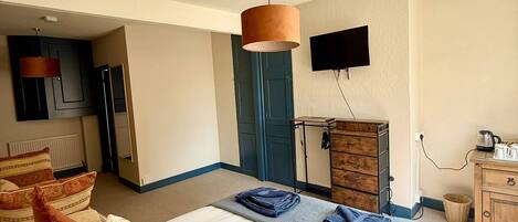 A hotel room with a bed, a flat-screen TV, a wooden dresser, and a lamp.