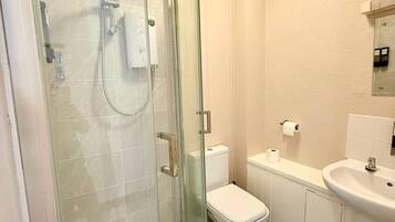 Un baño con ducha de vidrio, inodoro, lavamanos y espejo.