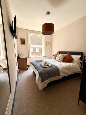 A bedroom with a bed, a dresser, a radiator, a window, and a hanging lamp. - The Lamb Inn (Marlborough)