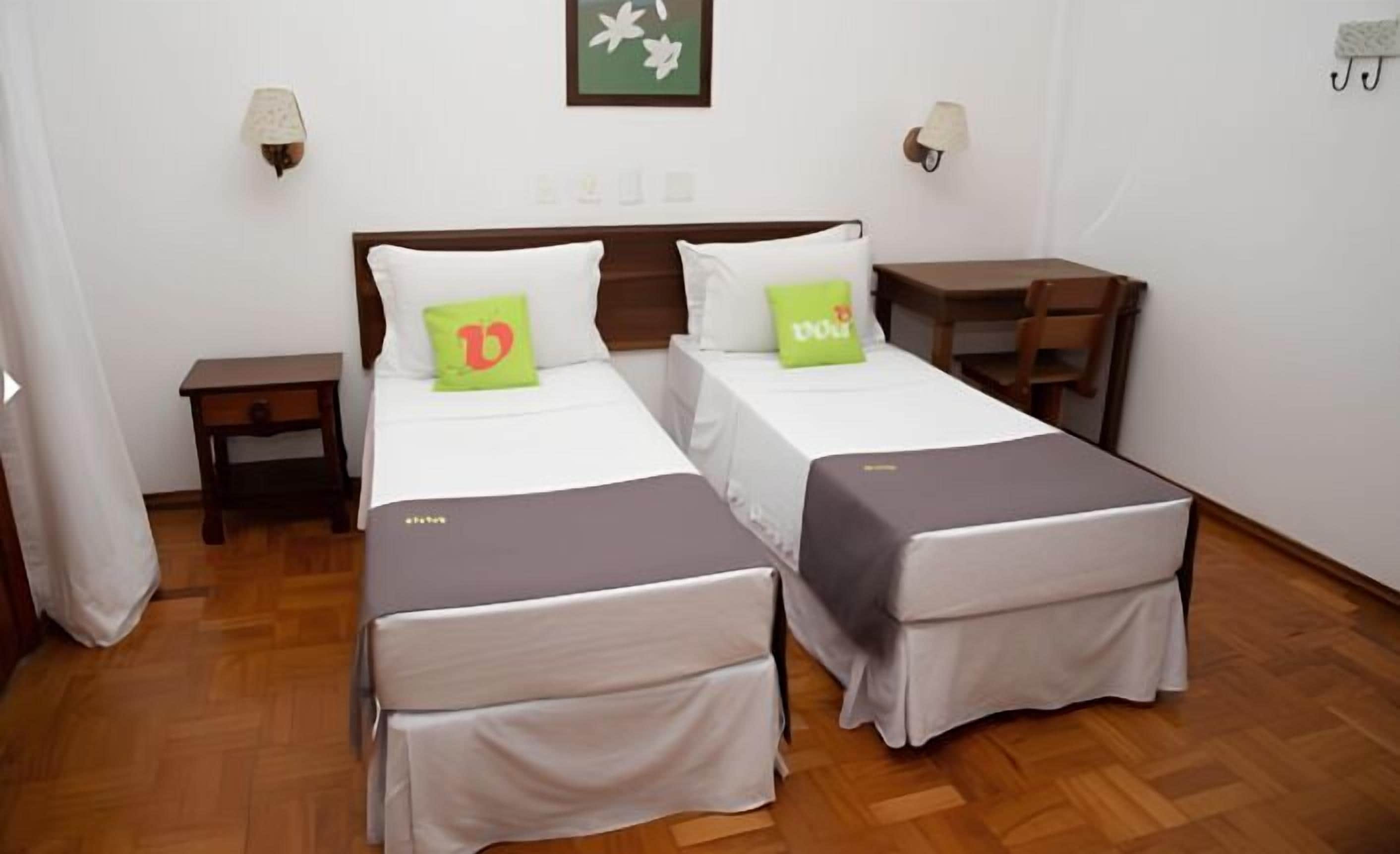 Habitación doble con dos camas, un escritorio pequeño y una silla.