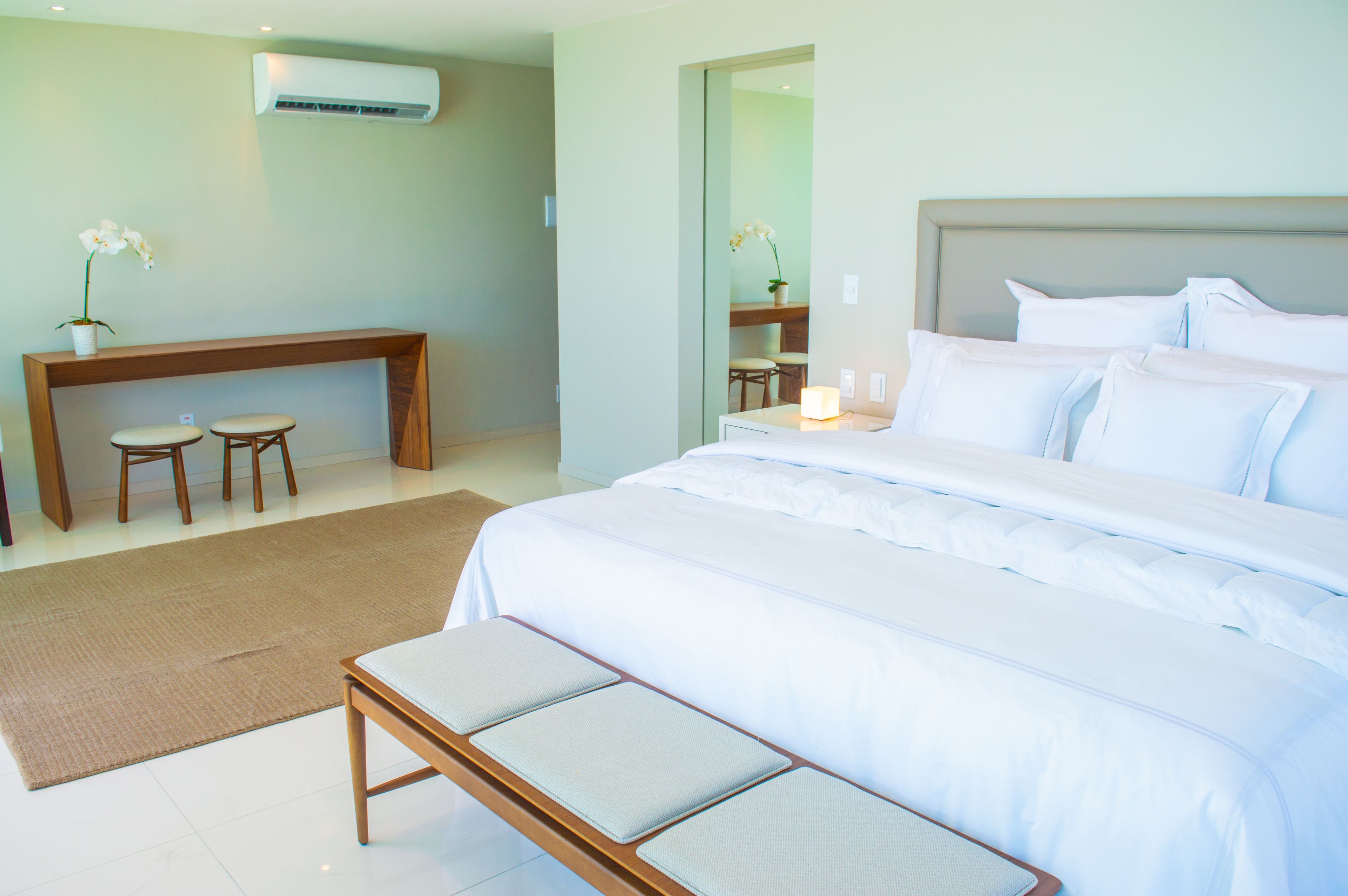 A bedroom with a large bed, bedside tables, a desk, two chairs, and a mirror.
