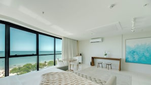 Un dormitorio moderno con una cama grande, vistas al océano, un comedor y un cuadro grande en la pared.