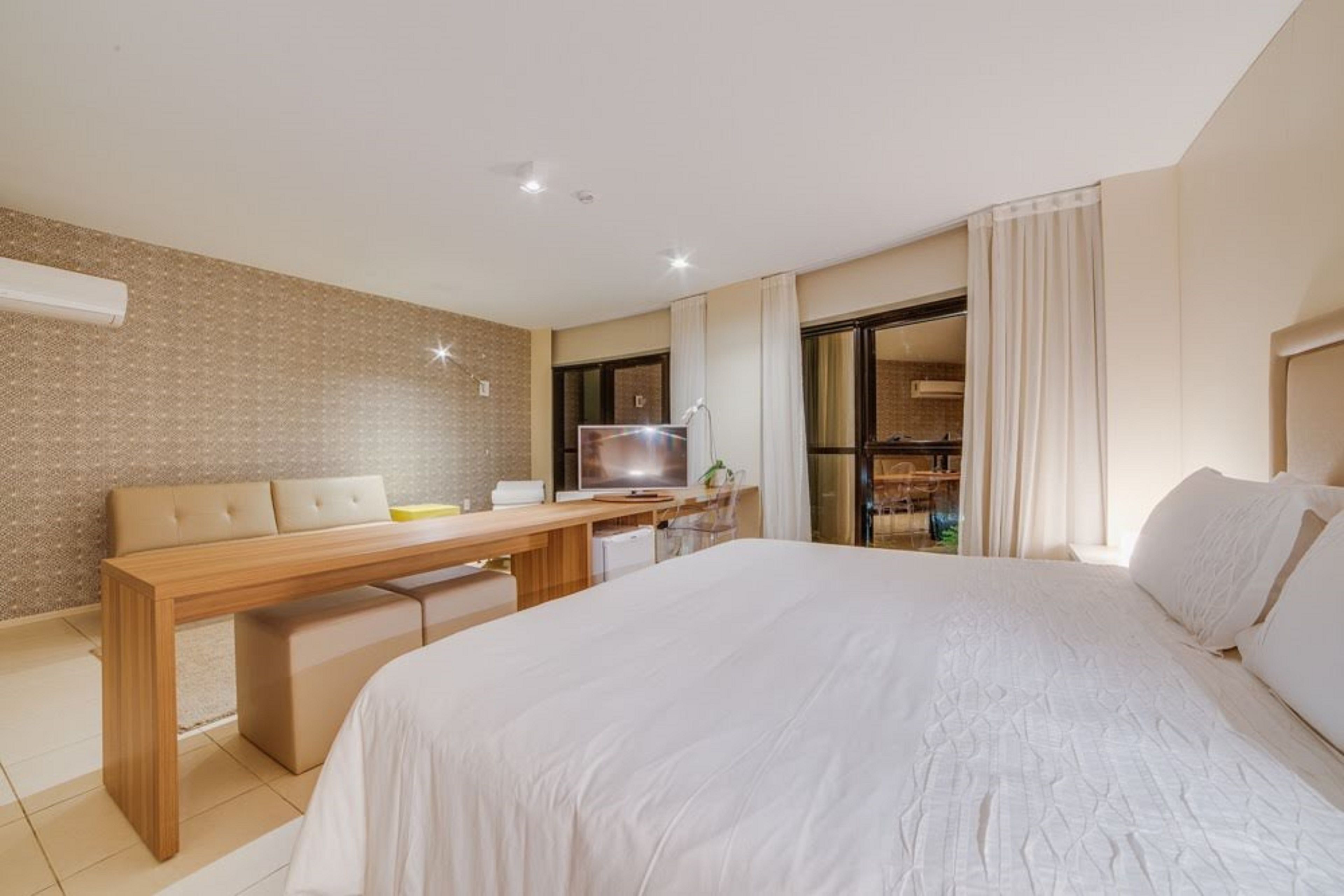 Camera d'albergo moderna con un letto grande, una scrivania in legno, una televisione e vista all'esterno.
