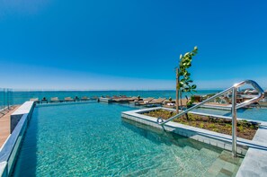 A clear blue pool with lounge chairs and a view of the ocean. - Meridiano Hotel (Maceió)