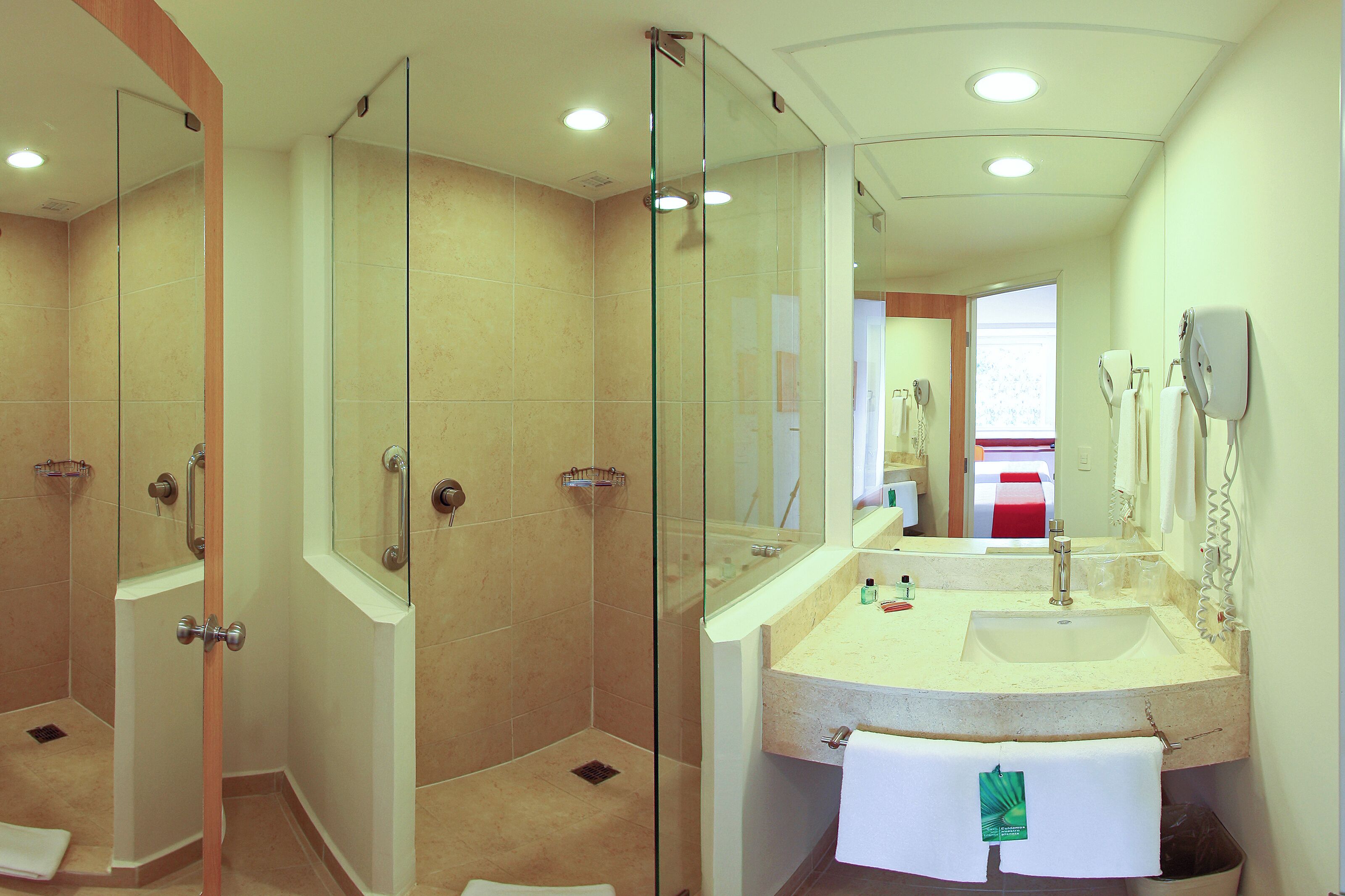 Un baño moderno con ducha envuelta en vidrio, un lavamanos con toalla y un espejo.