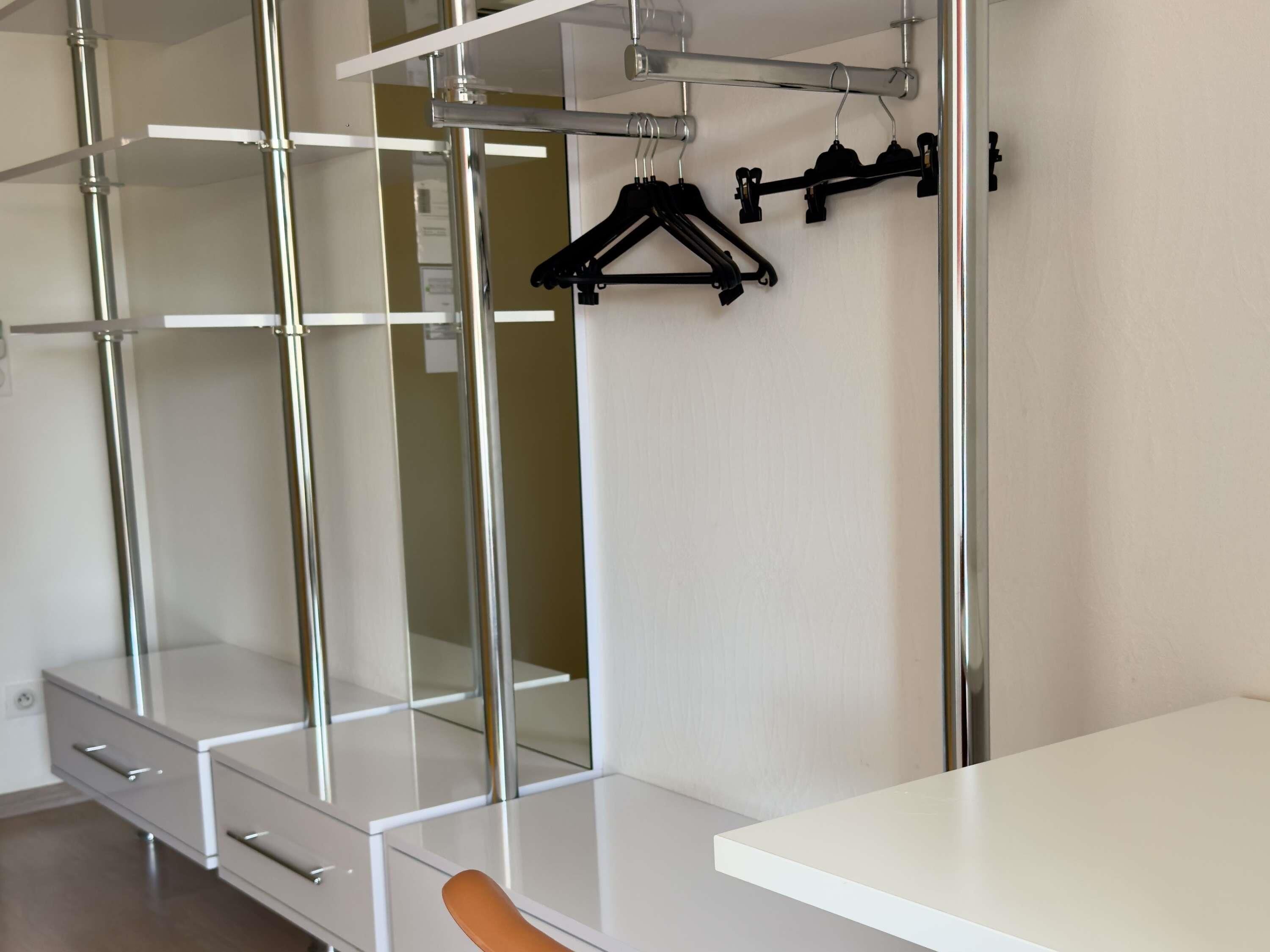 Une chambre moderne avec une armoire blanche, un miroir et une table blanche.